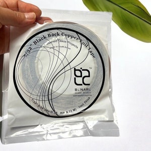 May include: A roll of 7/32 inch black back copper foil tape for stained glass projects. The tape is 36 yards long and 1 mil thick. Made in South Korea.  The label reads "7/32" Black Back Copper Foil Tape" and "BINARI Glass Studio".