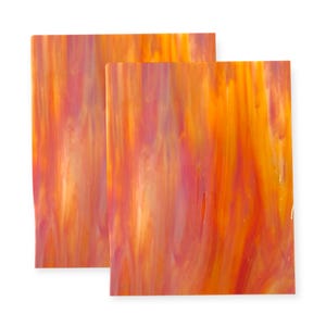 May include: Two rectangular sheets of stained glass with a vibrant blend of orange, yellow, and pink hues. The glass has a streaked, flowing pattern, creating a dynamic and colorful appearance. Ideal for craft projects.