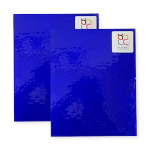 May include: Two sheets of glossy, deep blue material. Each sheet has a textured surface and a white sticker with colorful logo and text that reads "BINARI Glass Studio". The sheets are rectangular and appear to be made of glass or a similar material.