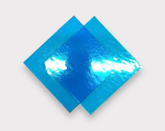 Puede incluir: Dos cuadrados de vidrio azul iridiscente superpuestos, creando una forma de diamante.