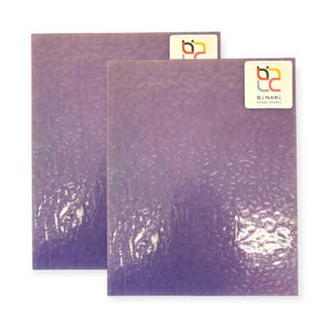 May include: Two textured, rectangular glass sheets in shades of purple. Each sheet has a unique, bubbly surface. The top right corner of each sheet has a sticker with the text "BINARI Glass Studio" and a logo.