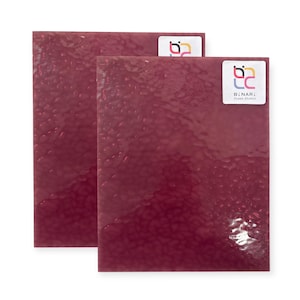 May include: Two rectangular sheets of textured, deep red glass. Each sheet has a bubbly, hammered appearance. The upper right corner of each sheet has a white sticker with a colorful logo and the text "BINARI Glass Studio."