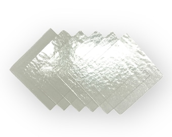 May include: A stack of six clear, slightly textured, square-shaped sheets of edible silver leaf.