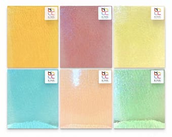 May include: Six square glass tiles arranged in a grid, featuring colors of yellow, mauve, pale yellow, turquoise, peach, and light green. Each tile has a textured, rippled surface and a small white square label in the corner with the text BINARI.