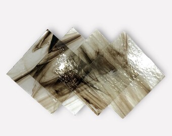 May include: Four diamond-shaped glass tiles with a marbled pattern in shades of brown and white. The tiles are arranged in a slightly overlapping pattern, creating a textured effect. The glass has a glossy finish, reflecting light.