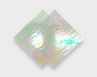 May include: Two iridescent squares of glass, one overlapping the other, with a light green hue and a shimmering, pearlescent finish.