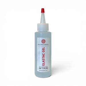 May include: A clear plastic bottle of Glastac Gel with a red tip. The label includes the text "BULLSEYE GLASS CO." and "GLASTAC GEL". The bottle contains 4 fl oz (120 ml) of gel. The product is from 12/06/2022.