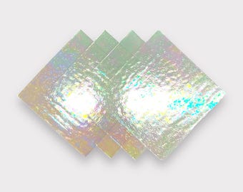 May include: Four iridescent, square-shaped glass tiles with a textured surface. The tiles are stacked on top of each other, creating a diamond shape.
