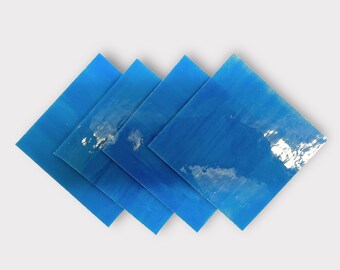 May include: Four blue square pieces of glass, stacked on top of each other, with a slight overlap. The glass is translucent and has a slight shimmer to it.