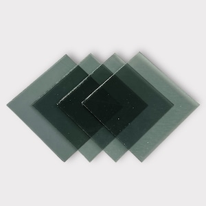 May include: Four overlapping square pieces of dark green glass.