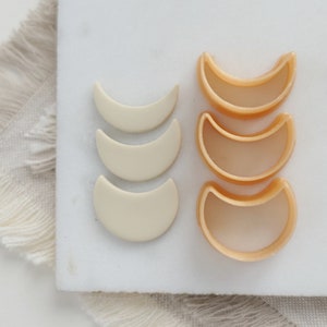 Può includere: Un set di quattro stampini per biscotti a forma di mezzaluna. Due sono bianchi e due sono di colore arancio chiaro.