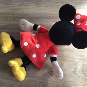 May include: A red and white polka dot plush toy of Minnie Mouse with black ears and a red bow with white polka dots.
