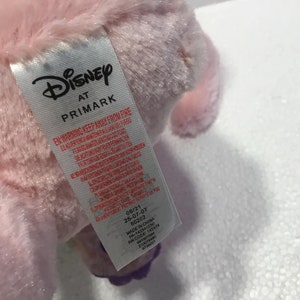 May include: Pink plush toy with a Disney at Primark tag. The tag has a warning to keep away from fire and includes manufacturing information.