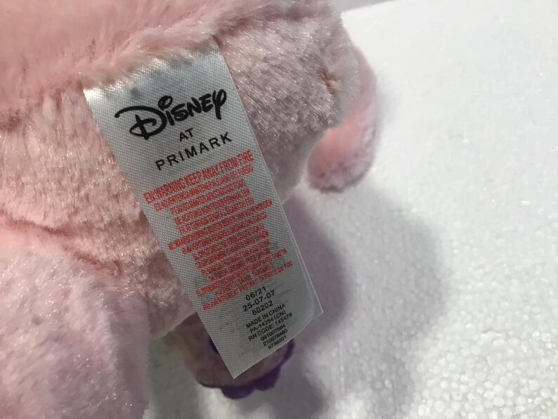 May include: Pink plush toy with a Disney at Primark tag. The tag has a warning to keep away from fire and includes manufacturing information.