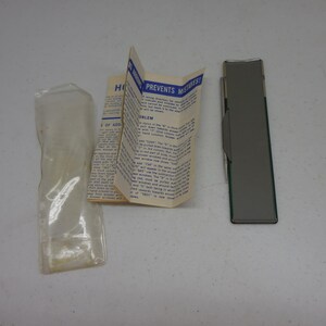Peut inclure: Une machine à additionner mécanique vintage avec un corps rectangulaire métallique, un stylet fin, un manuel d'instructions en papier plié avec le texte "PREVENTS MISTAKES!" et une pochette de protection en plastique transparent.