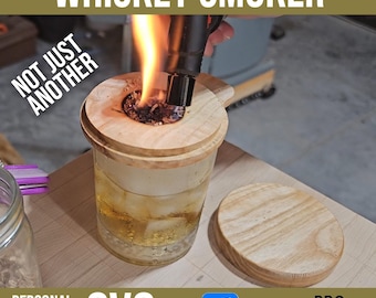 May include: A wooden whiskey smoker with a lid and a glass of whiskey inside. The smoker is being lit with a torch. The text "NOT JUST ANOTHER" is visible in the image. The text "SVG + VCarve PRO" is also visible in the image.