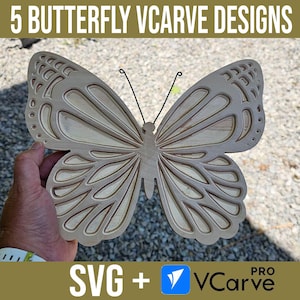 May include: A wooden butterfly cutout with intricate details, perfect for a VCarve project. The butterfly is held in a hand, showcasing its size and detail. The image includes the text "5 BUTTERFLY VCARVE DESIGNS" and "SVG + VCarve PRO".