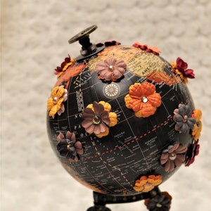Upcycled World Map Globe with handmade paper flowers with rhinestone centers on black stand.
