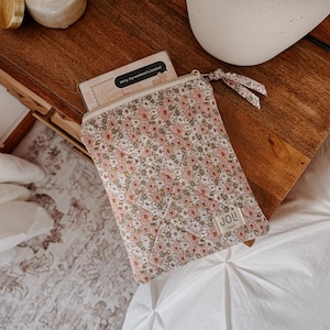 Puede incluir: Un pequeño estuche con estampado floral, cierre de cremallera y una etiqueta de tela que dice "JOL". El estuche contiene una tarjeta con el texto "sorry, my weekend is booked". El estuche está sobre una superficie de madera.