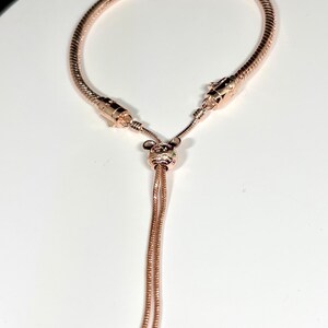 Op de afbeelding: Verstelbare armband in ros&eacute;goud met een slangenkettingontwerp. De armband heeft een Mickey Mouse-vormige bedel met kleine, kleurrijke edelstenen. De uiteinden van de armband hebben twee kleine, ronde kralen.