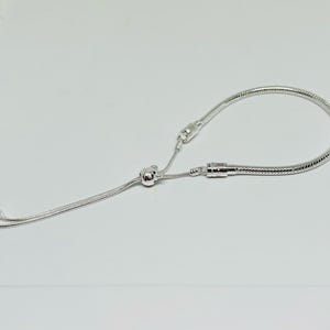 K&ouml;nnte beinhalten: Ein silbernes Kettenarmband mit einem Schiebeverschluss. Das Armband ist aus einer Schlangenkettenart gefertigt.