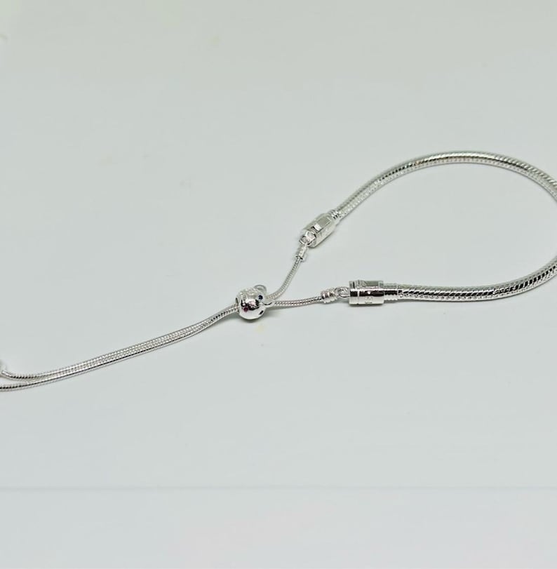 K&ouml;nnte beinhalten: Ein silbernes Kettenarmband mit einem Schiebeverschluss. Das Armband ist aus einer Schlangenkettenart gefertigt.