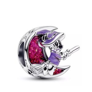 May include: A silver charm featuring a cartoon character in a purple witch costume riding a broom on a crescent moon. The moon has a pink glittery center and is engraved with text. A whimsical Halloween-themed charm.