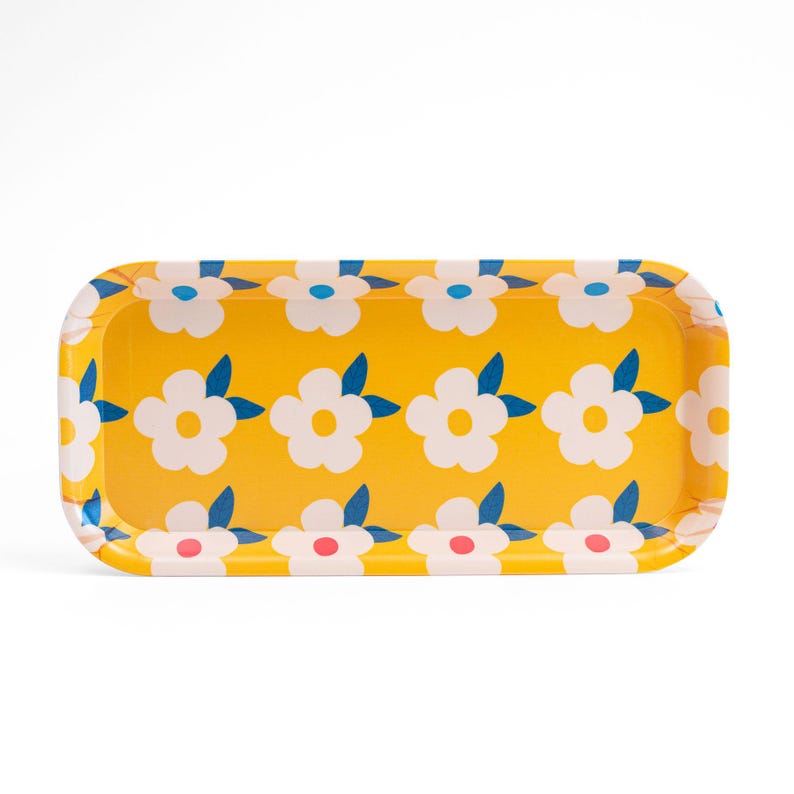 May include: A yellow rectangular tray with a floral pattern. The tray has white flowers with blue leaves and pink centers.