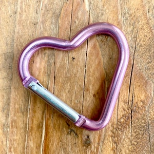 May include: A pink metal heart-shaped carabiner with a silver metal clasp.