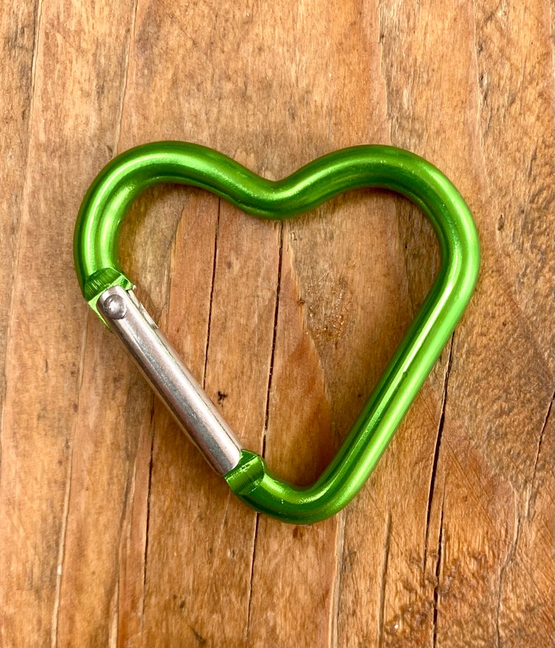 May include: A green heart-shaped carabiner with a silver metal clasp.