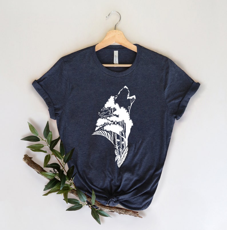 May include: A dark blue t-shirt with a white graphic of a wolf howling with trees growing out of its silhouette.