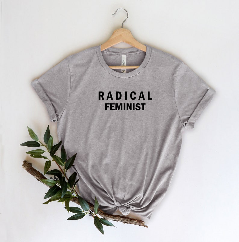 Puede incluir: Una camiseta gris con el texto "RADICAL FEMINIST" impreso en negro en la parte delantera.