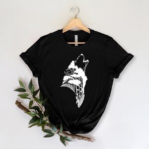 May include: Black t-shirt with a white graphic of a wolf howling with trees growing out of its head.