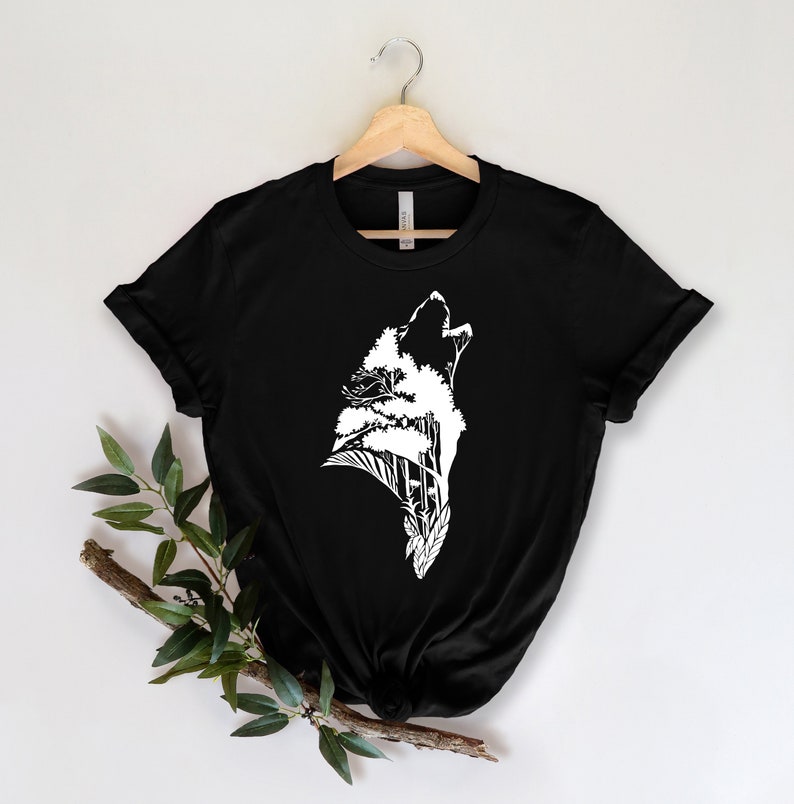 May include: Black t-shirt with a white graphic of a wolf howling with trees growing out of its head.