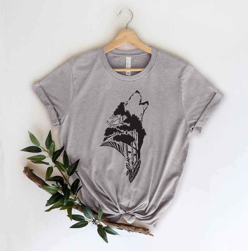 May include: A heather grey t-shirt with a black silhouette of a wolf howling, with trees and leaves forming the wolf's body.