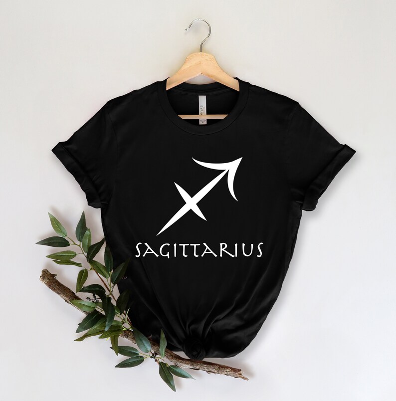 May include: Black t-shirt with a white Sagittarius zodiac symbol and the word "SAGITTARIUS" printed on the front.