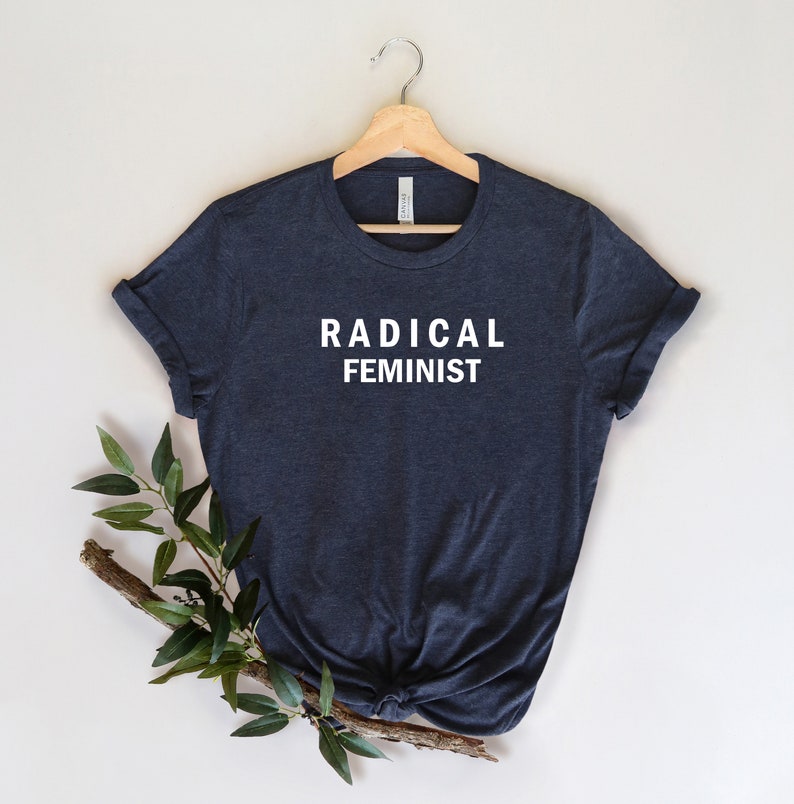 Puede incluir: Una camiseta azul oscuro con el texto "RADICAL FEMINIST" impreso en blanco en la parte delantera.
