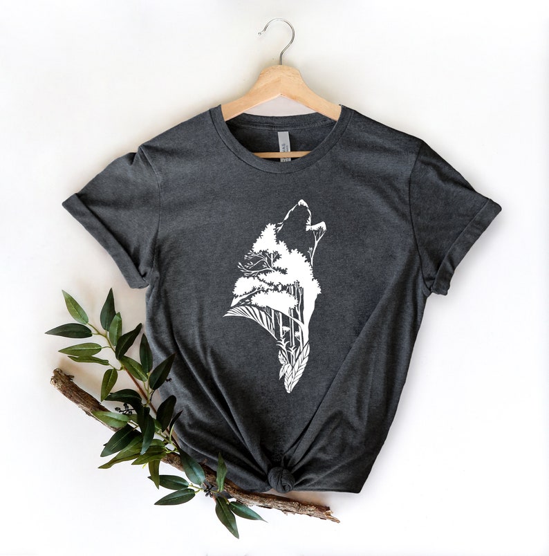 May include: A dark gray t-shirt with a white graphic of a wolf howling with trees growing out of its head.
