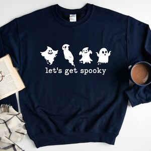 May include: A navy blue sweatshirt with a white graphic of four ghosts and the text "let's get spooky".