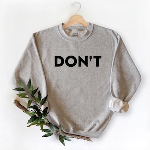 May include: A gray sweatshirt with the word "DON'T" printed in black on the front.