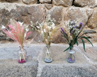 Può includere: Tre vasi di vetro con fiori secchi. Il vaso a sinistra ha fiori secchi rosa e bianchi. Il vaso al centro ha fiori secchi bianchi e beige. Il vaso a destra ha fiori secchi viola e bianchi.