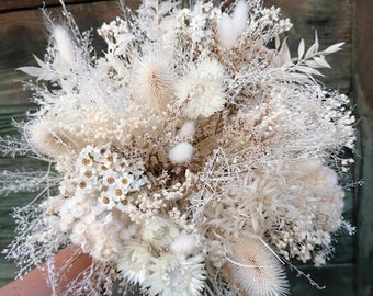 Può includere: Un bouquet di fiori secchi bianchi con diverse texture e forme, tra cui fiori bianchi soffici, ramoscelli delicati e accenti spinosi.