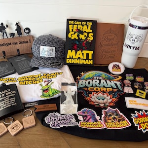 May include: A collection of merchandise including a black hat, a book titled The Gate of the Feral Gods, a white water bottle with the text IWKYM, a black flask labeled Carl's Jug O Boom, a white t-shirt, a black tote bag, and various stickers.