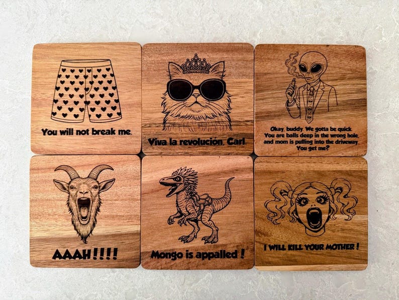 May include: A set of six square wooden coasters featuring laser-engraved illustrations and text. Designs include heart-patterned boxers, a cat with sunglasses and a crown, an alien, a screaming goat, a dinosaur, and a face with pigtails.