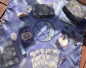 Puede incluir: Un fondo de tela morado con una variedad de cartas de tarot, cristales y una baraja de cartas llamada "The Deck of Celestials: Tarot Deck and Guidebook".