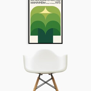 May include: A black framed poster with a green and yellow geometric design. The poster reads "Bundesgartenschau Mannheim 18.April-19.Oktober 1975".