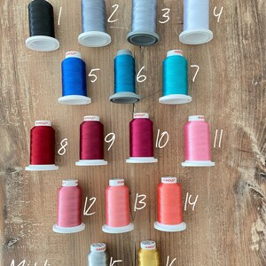 May include: Sixteen spools of Gunold embroidery thread arranged in four rows, numbered 1 through 16. The colors include black, various shades of gray, white, blue, teal, red, magenta, pink, coral, orange, silver, and gold metallic thread.