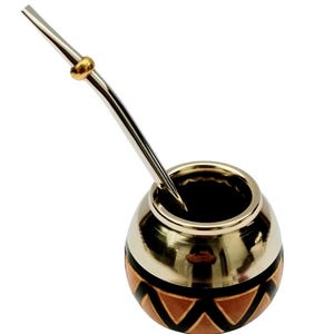 Puede incluir: Una calabaza mate de plata y marrón con una bombilla de plata. La calabaza tiene un patrón geométrico de triángulos en negro y naranja.