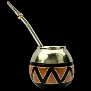 Puede incluir: Una calabaza plateada y negra con un patrón geométrico y una bombilla de paja plateada.