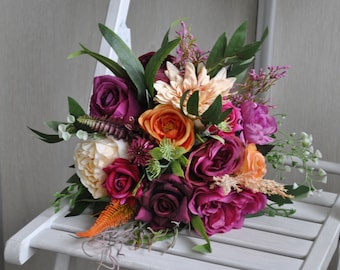 May include: A bouquet of artificial flowers in shades of pink, purple, orange, and cream. The bouquet features roses, peonies, and other floral elements.